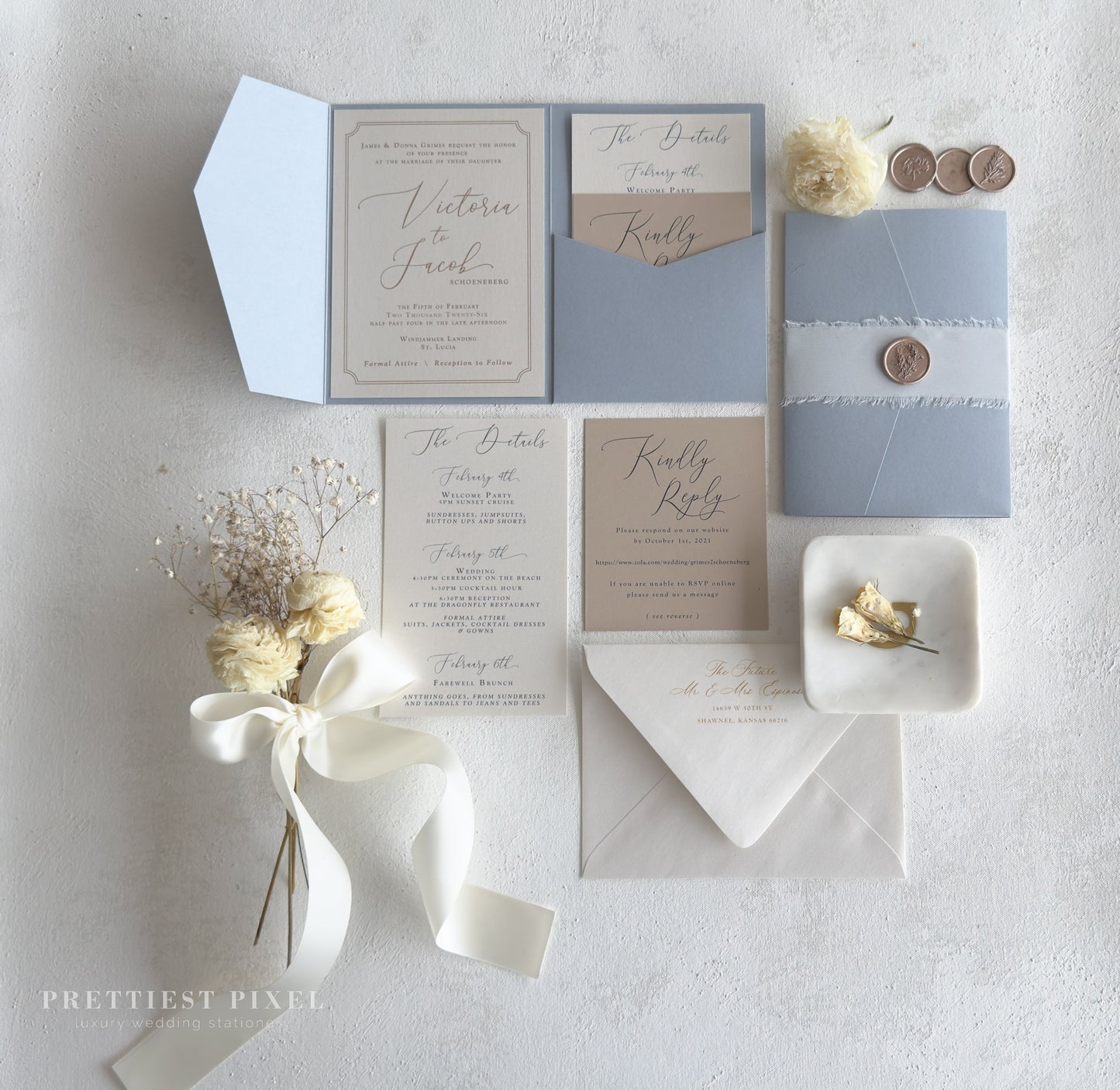 wedding stationery items, including an invitation, envelopes, and a small floral arrangement, all arranged on a white background.