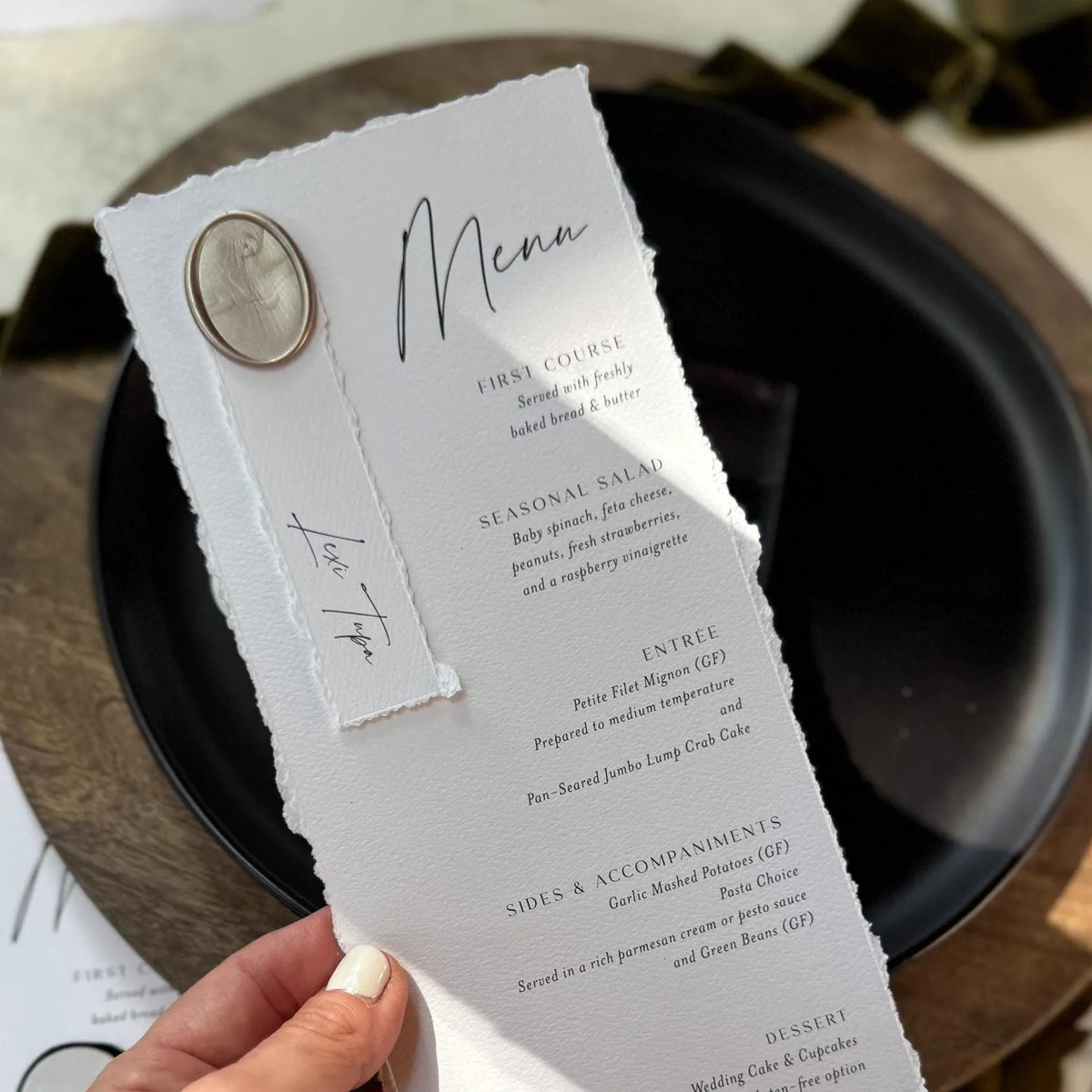A person is holding a menu with a white background and black text, featuring a decorative element on the left side.