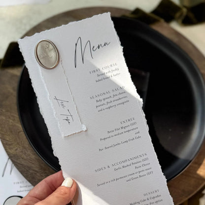 A person is holding a menu with a white background and black text, featuring a decorative element on the left side.