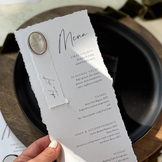 A person is holding a menu with a white background and black text, featuring a decorative element on the left side.
