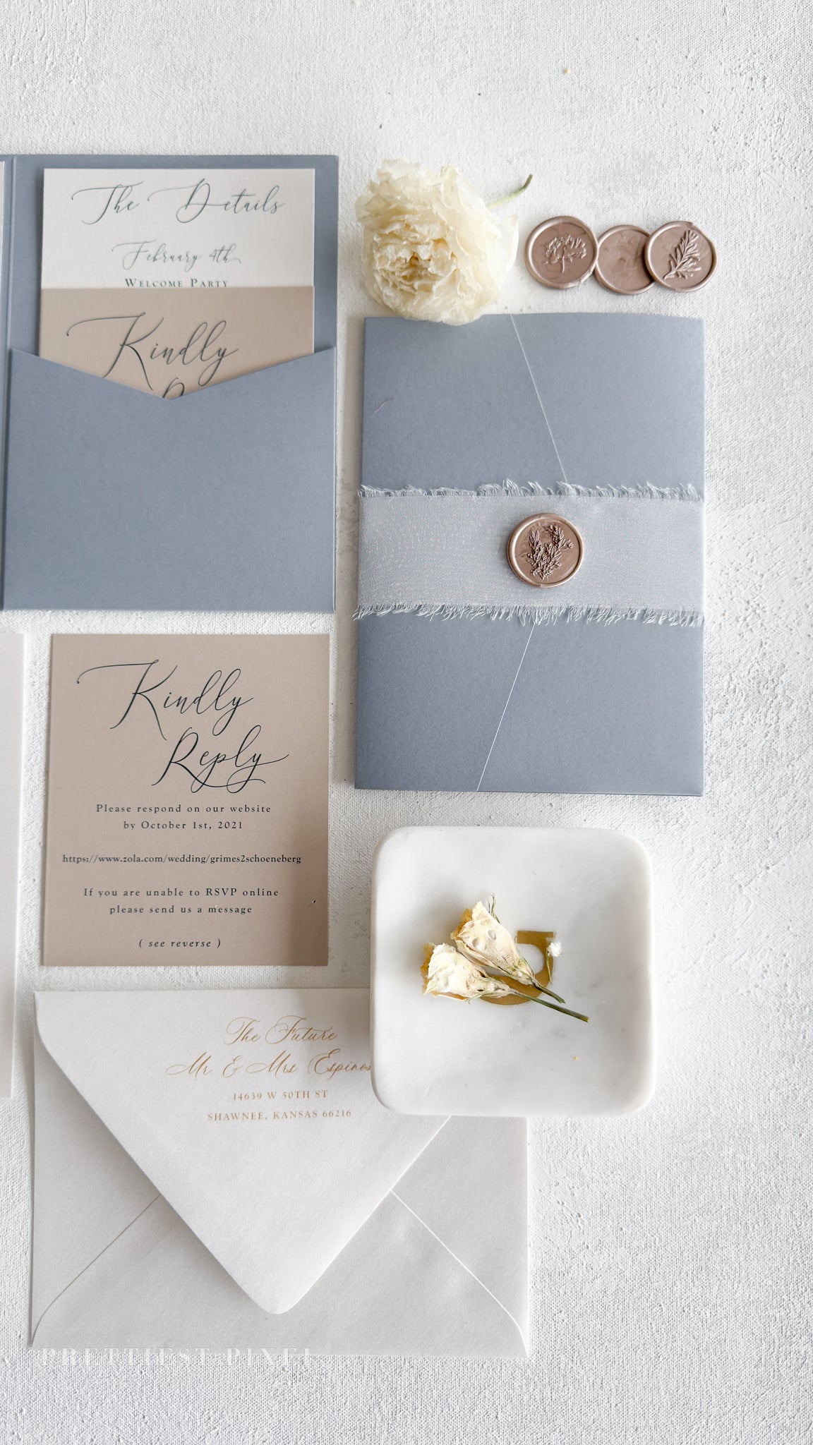 various wedding-related items, including a blue envelope, a white envelope, a small white plate with flowers, and some coins.