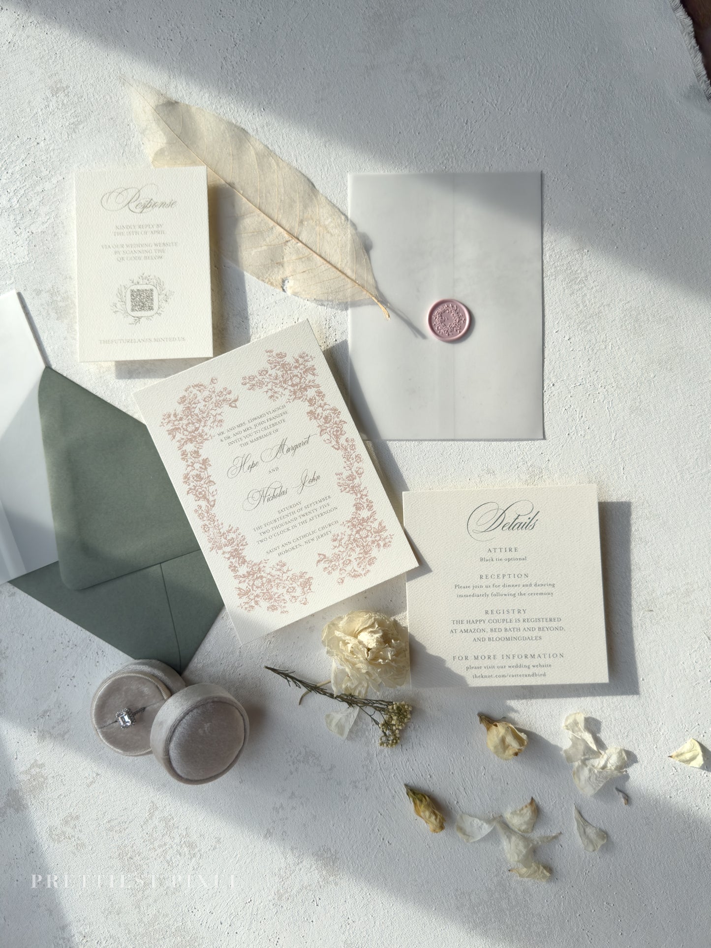 Wedding invitation set with envelopes, candles, and decorative elements on a textured surface.