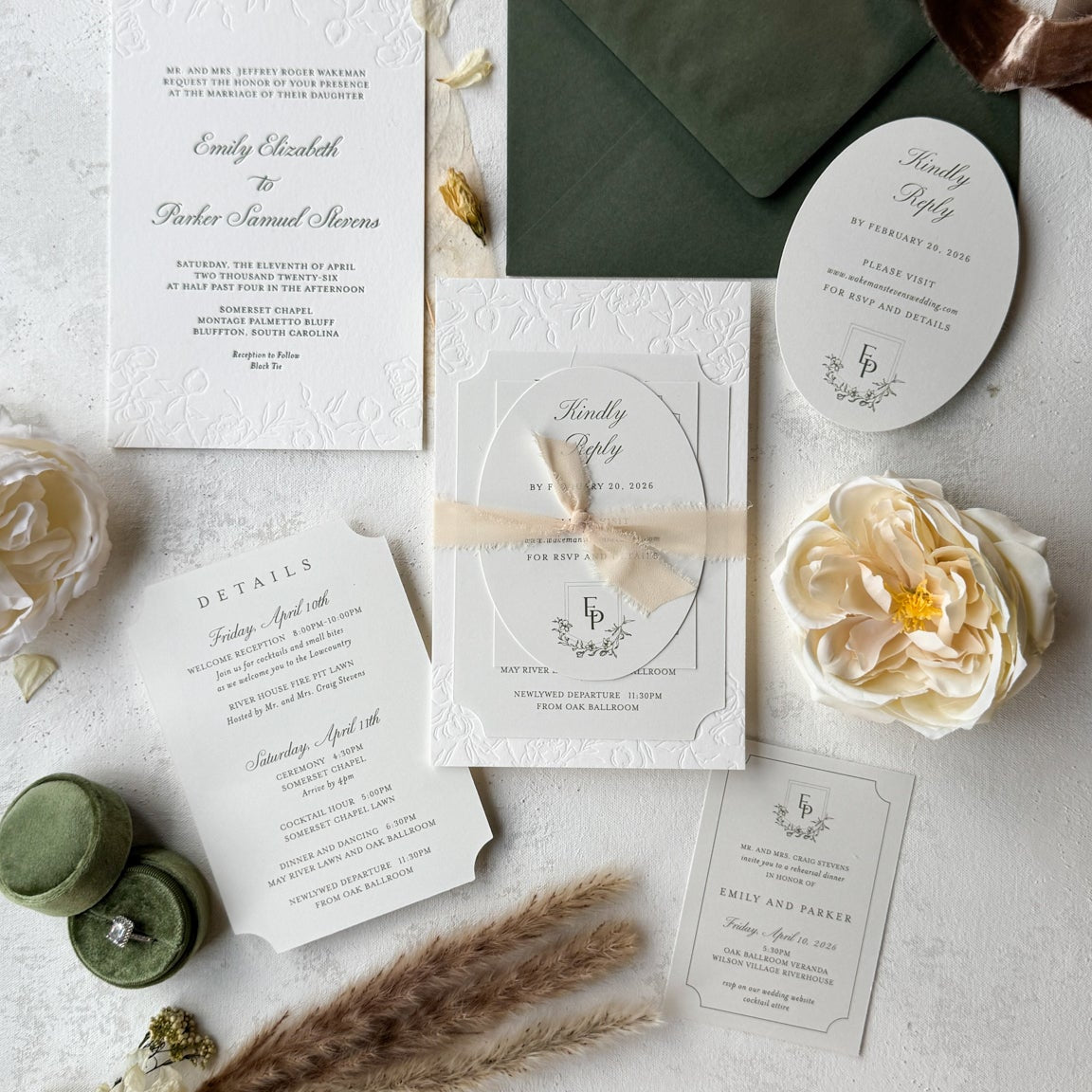 Wedding invitation set with green envelope, white cards, and decorative elements on a light surface.