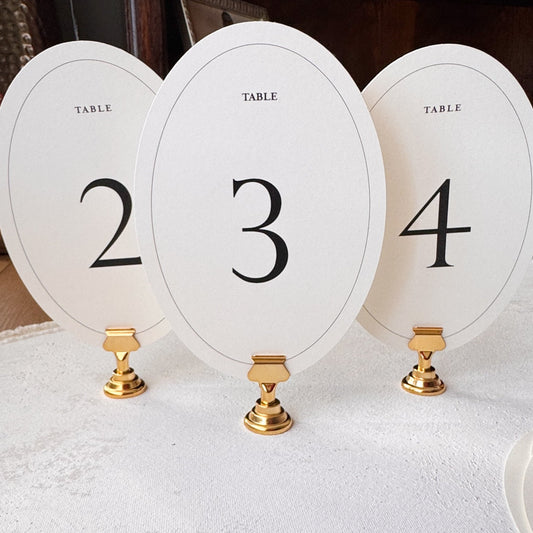 Three oval table number holders with numbers 2, 3, and 4 on a white surface.