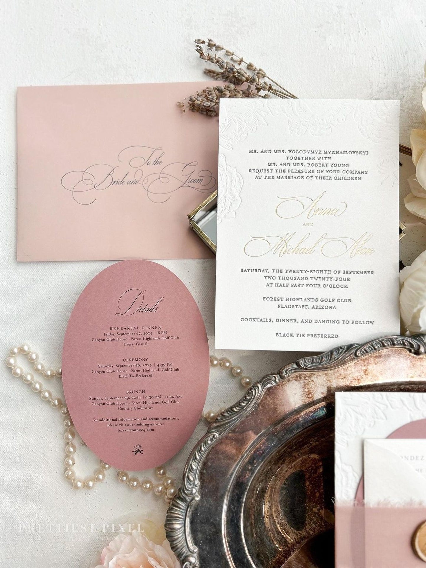 a wedding invitation with a pink envelope, a white wedding invitation, and some decorative elements such as pearls and flowers.