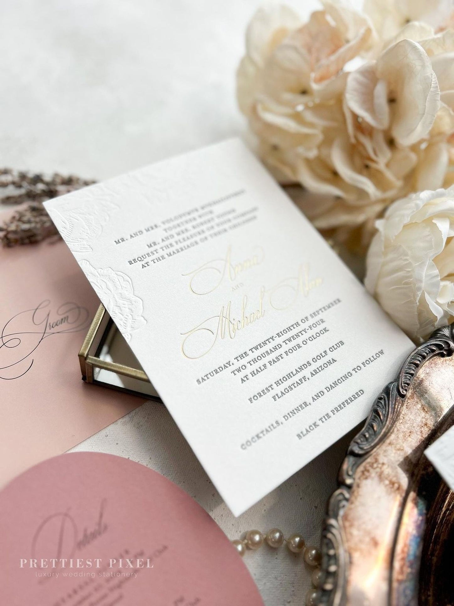 a wedding invitation card with elegant text and designs, surrounded by various decorative elements such as flowers, pearls, and a silver tray.