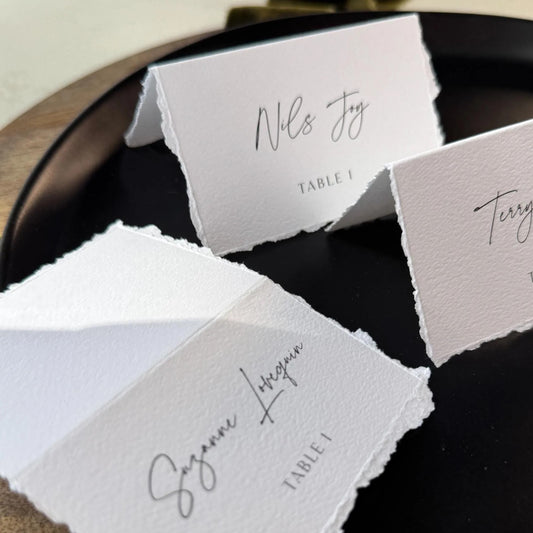 three white place cards with black text, placed on a black plate.