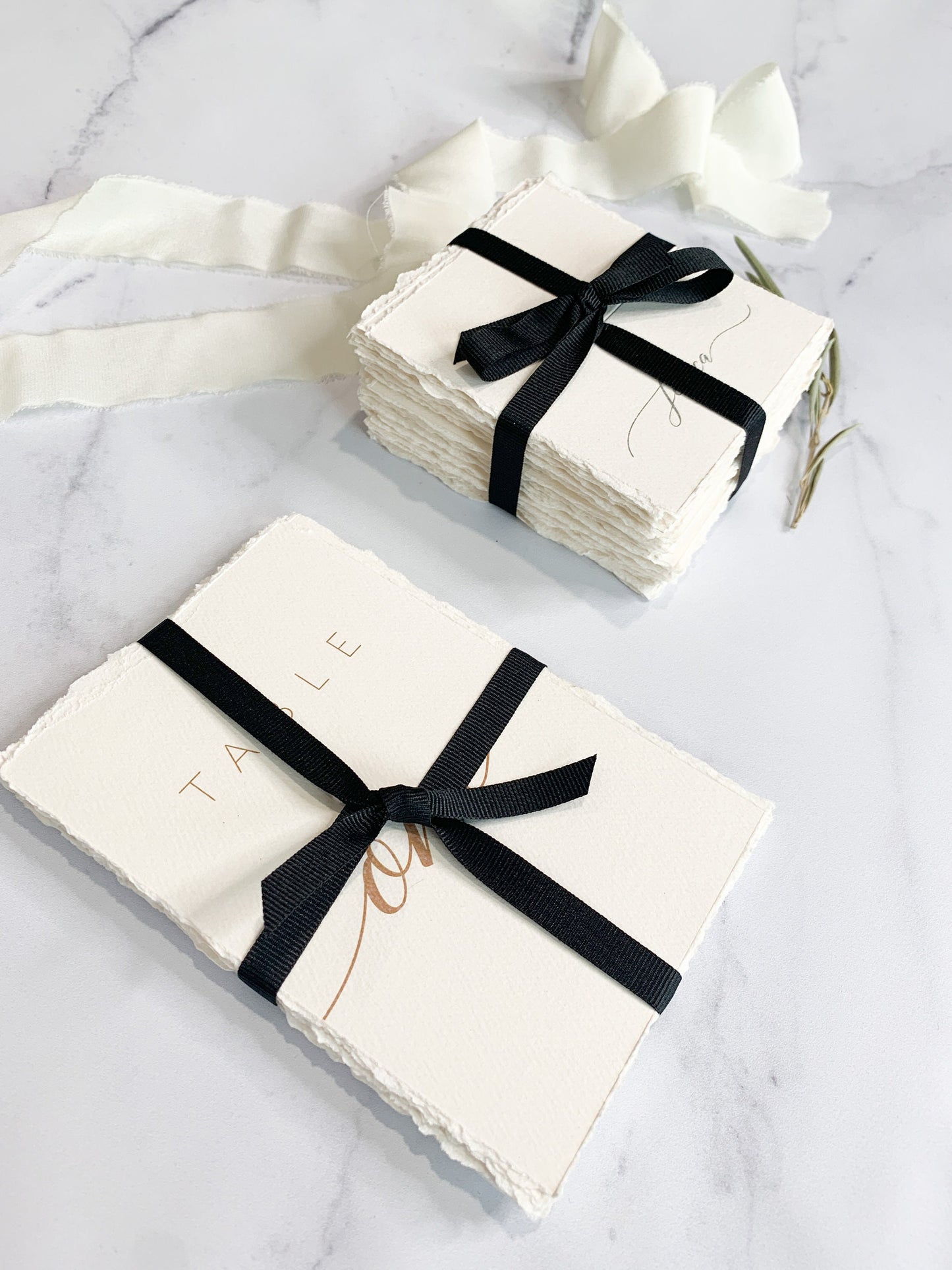 a stack of white cards with a black ribbon